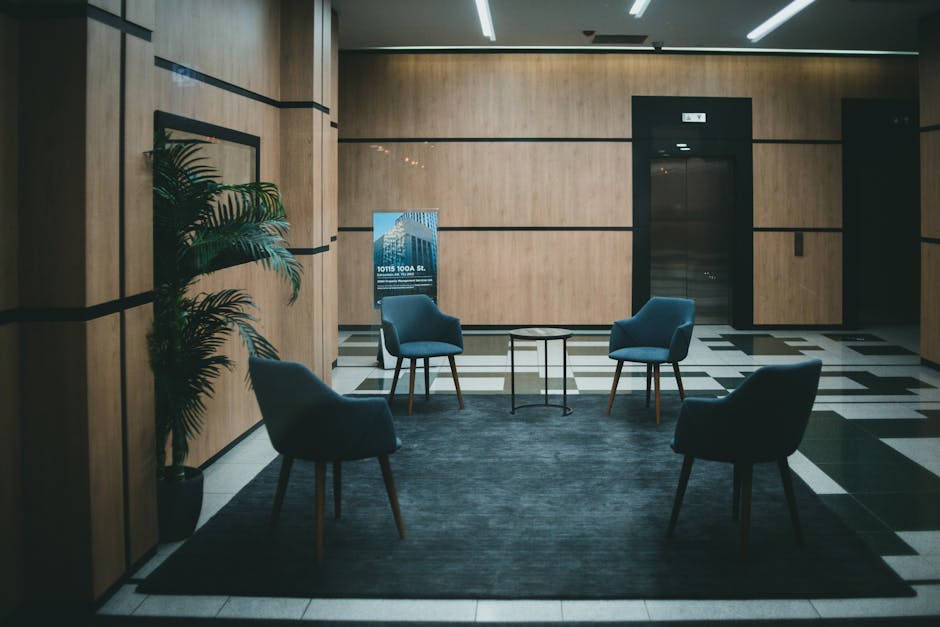 A stylish office lobby featuring chic chairs and a minimalistic design with a neutral tone.