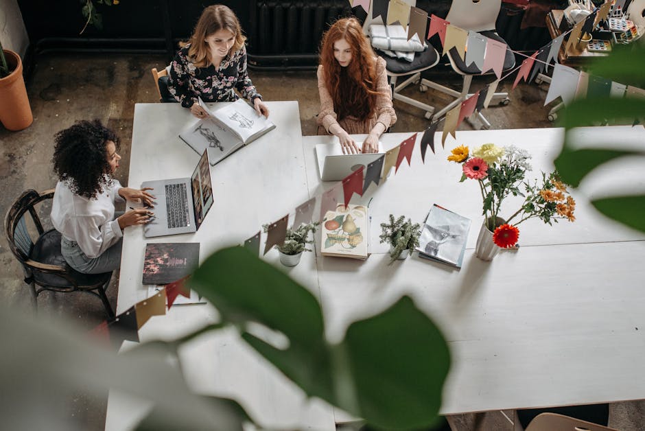 Top view of women working collaboratively at a decorated office table, fostering creativity and teamwork.